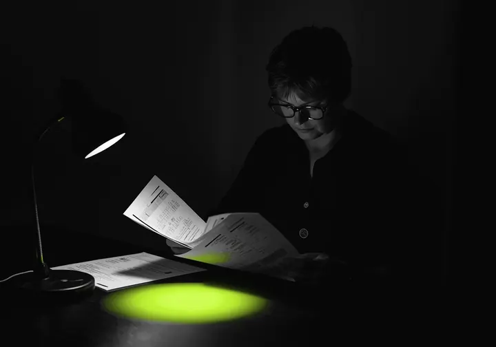 An auditor reviews printed reports at a desk at night